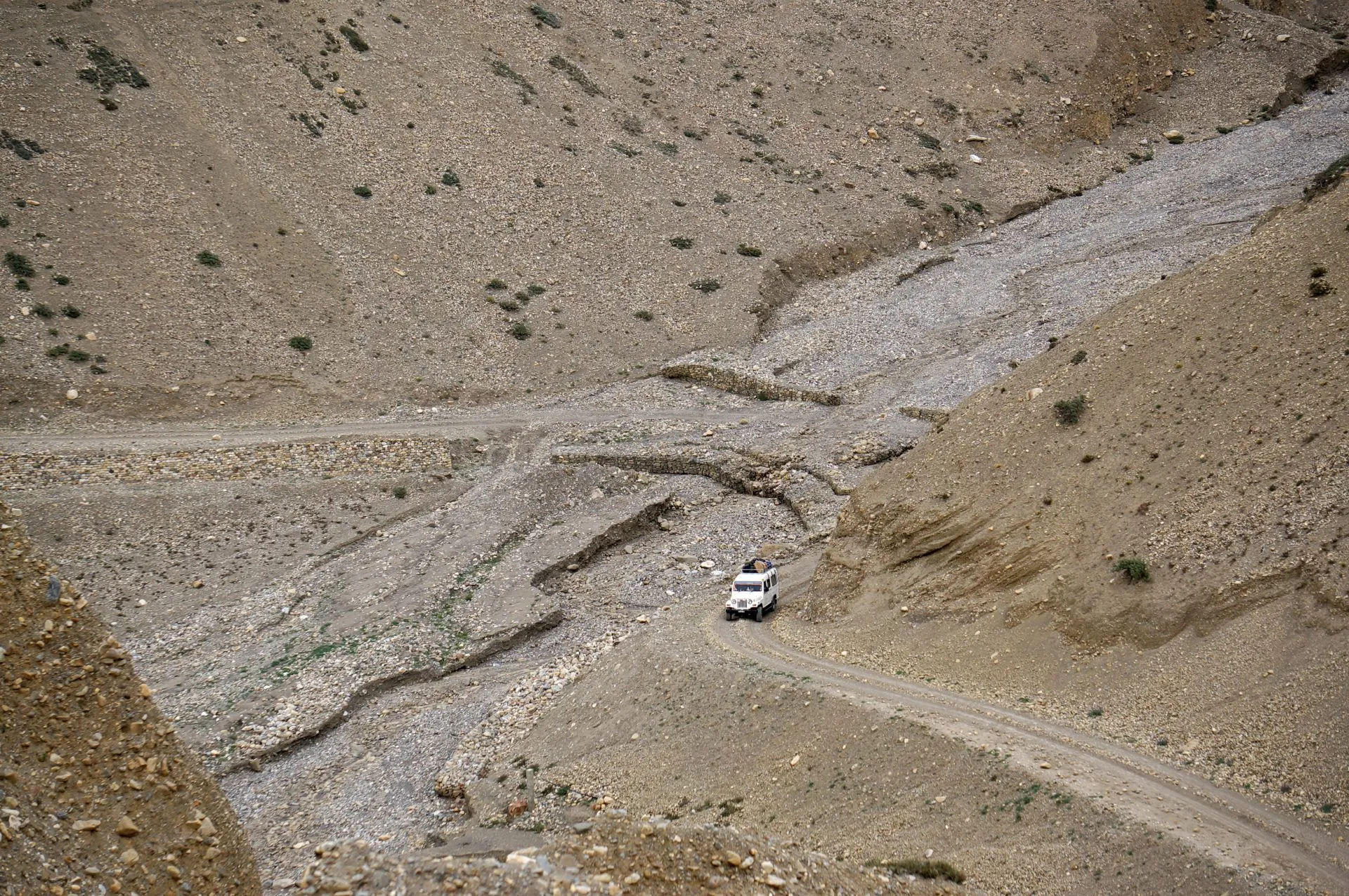 A tourist jeep carries tourists and their backpacks in a certain mountainous area, during trekking in the Upper Mustang of Nepal.